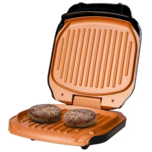 Grill électrique ouvert avec deux steaks hachés en cuisson sur plaques cuivrées.