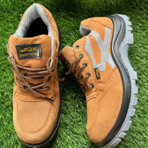 Paire de chaussures de sécurité marron clair avec semelle grise et doublure intérieure en maille, posée sur un gazon synthétique.