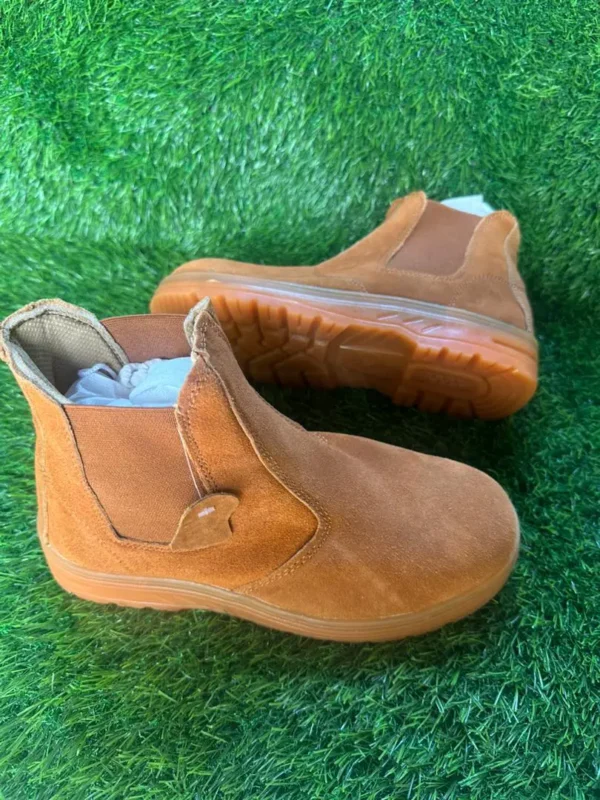 Chaussures de sécurité montantes – marron clair sans lacets Chaussures de sécurité montantes marron clair sans lacets, posées sur du gazon synthétique.